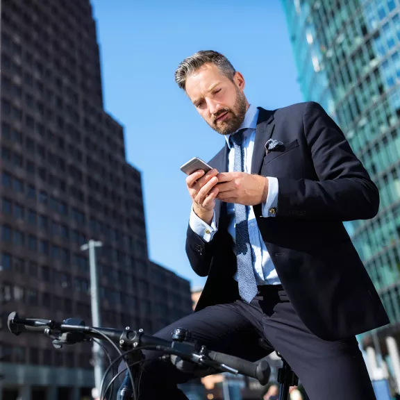 Business man on bicycle holding smartphone