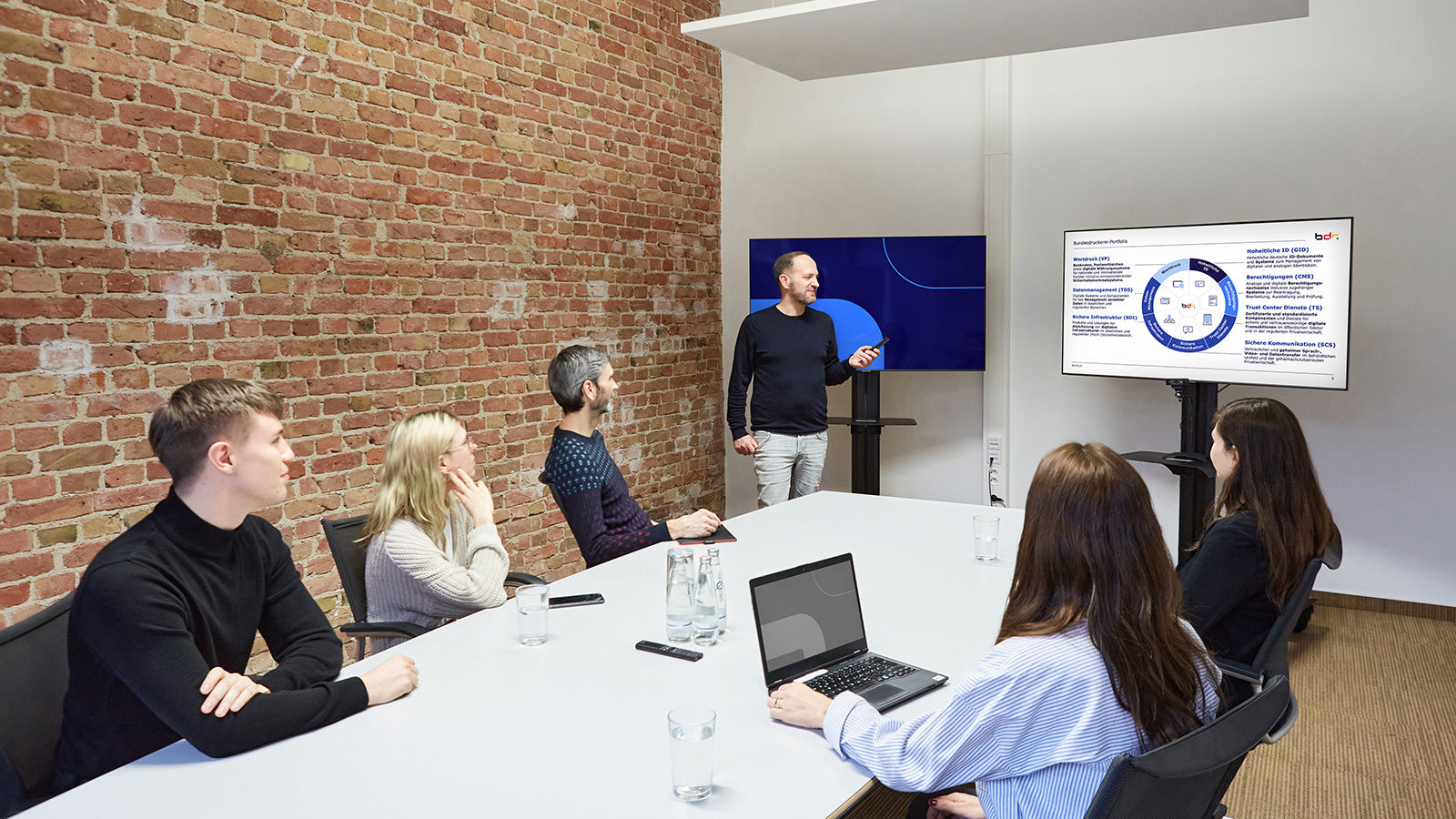 Photo showing employees of the Bundesdruckerei Group sitting around a meeting table and taking part in a training session