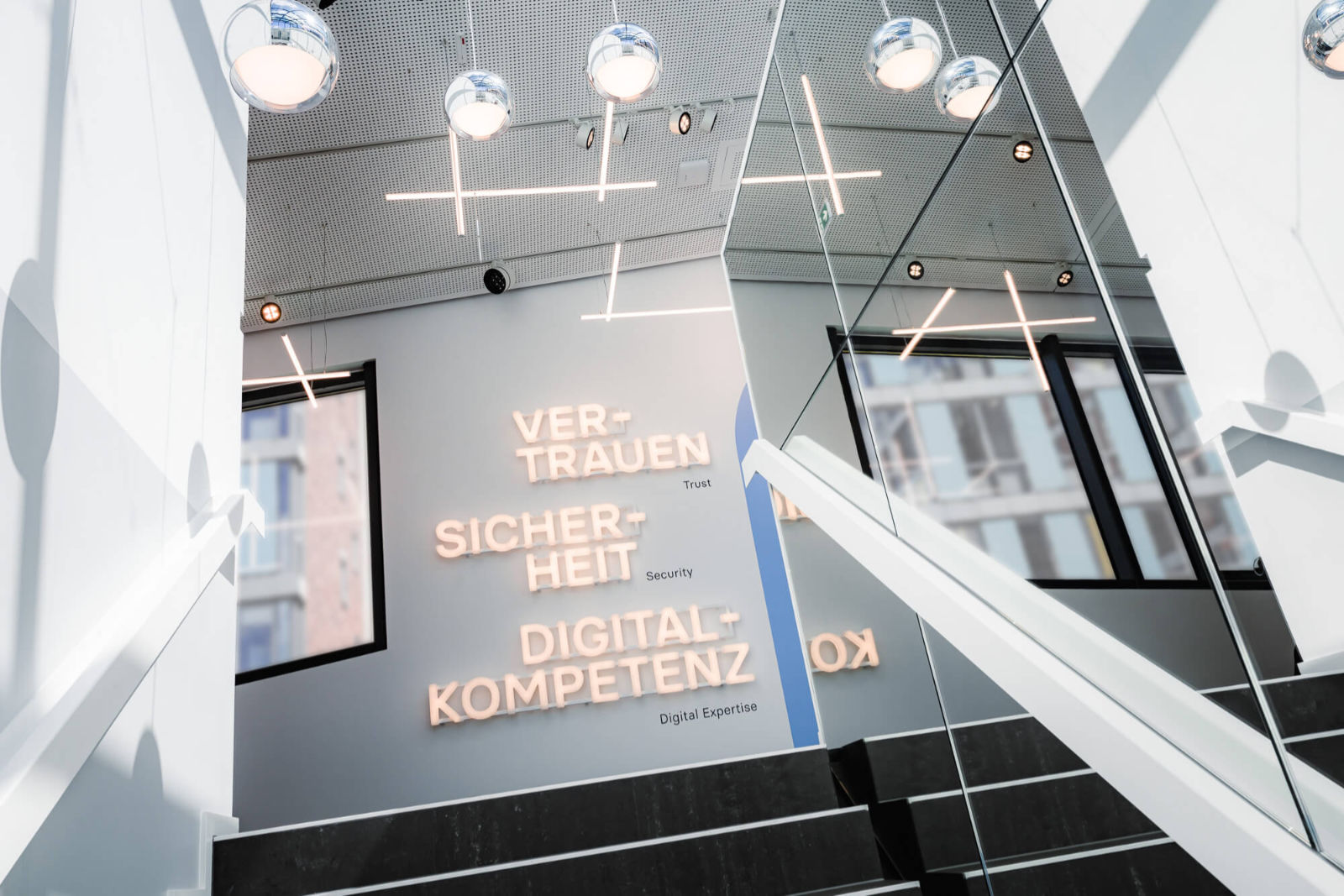 Das Bild zeigt eine Wand mit leuchtendem Schriftzug: Vertrauen, Sicherheit und digitale Expertise