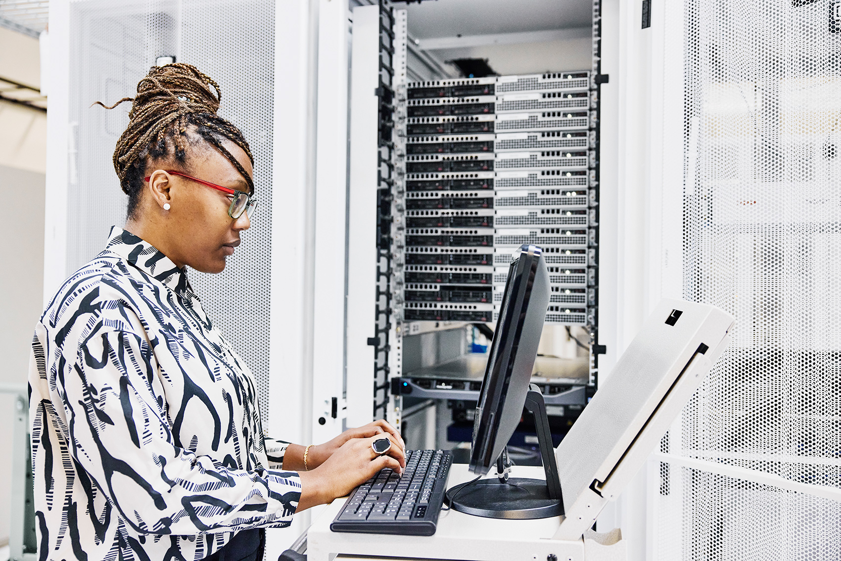 Eine Frau sitzt am Computer und arbeitet am Server.