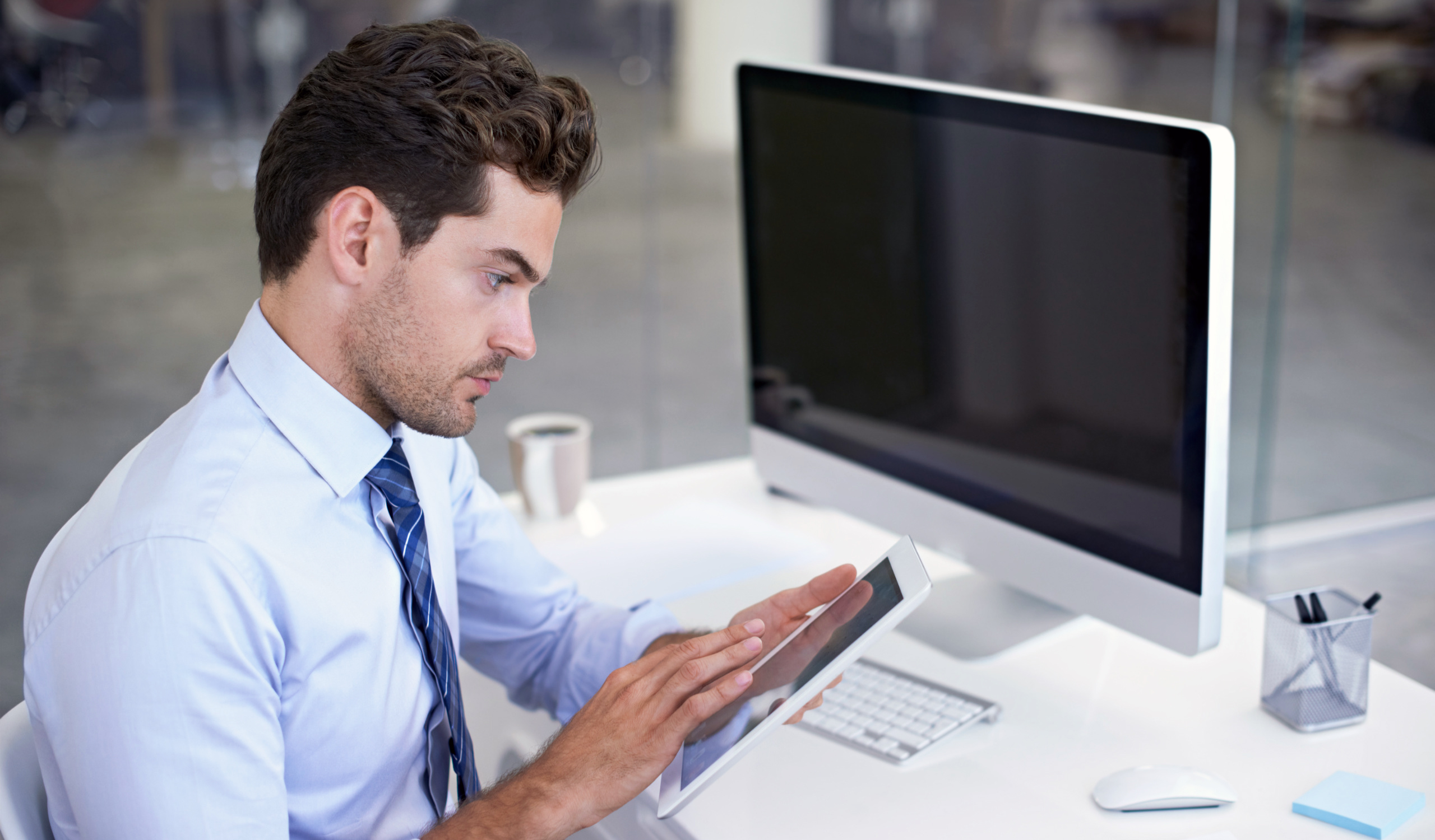 Mann arbeit mit Tablet und Computer am Schreibtisch