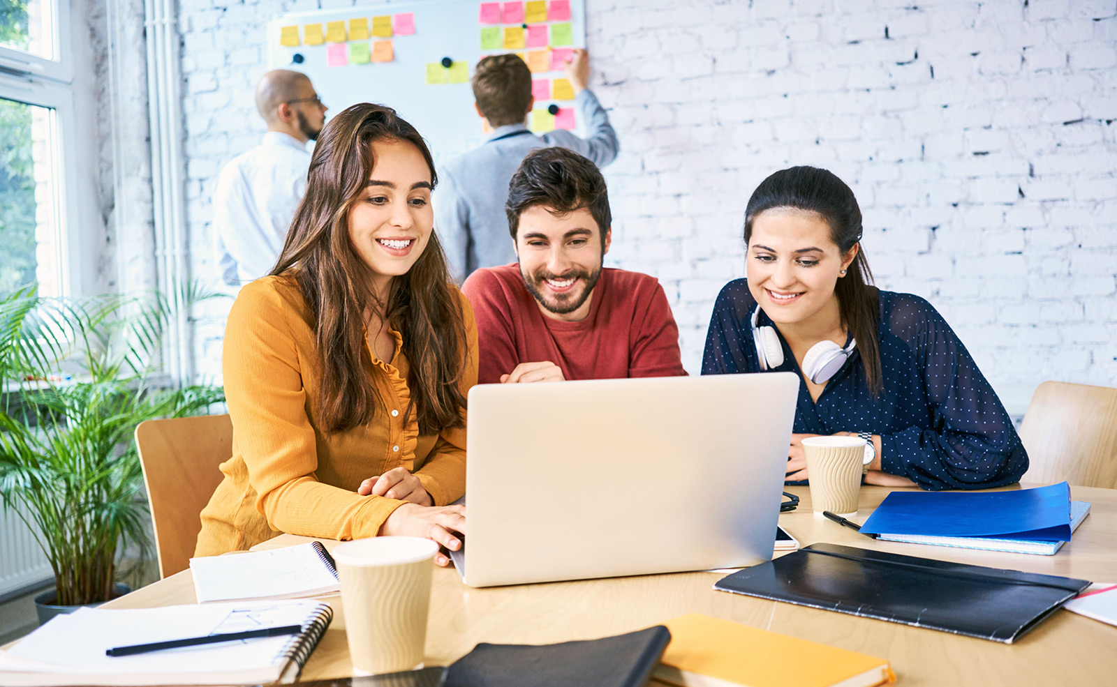 Three people sitting in front of a computer during a meeting