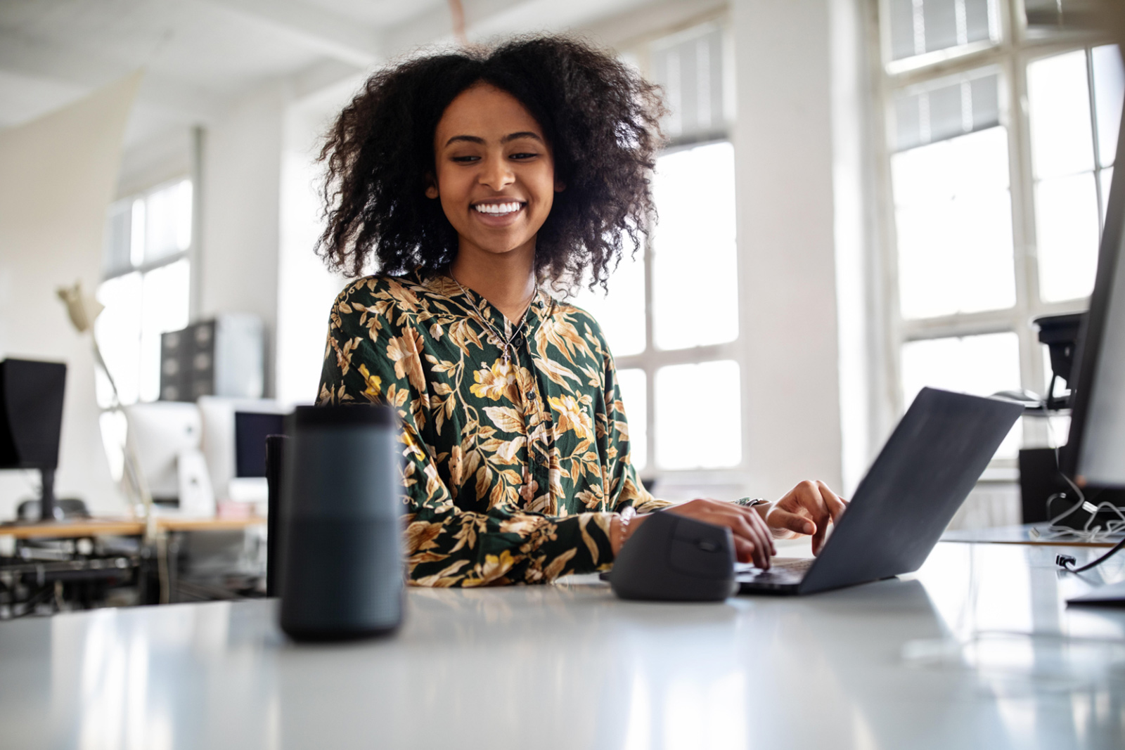 Woman at computer in office speaking through speaker