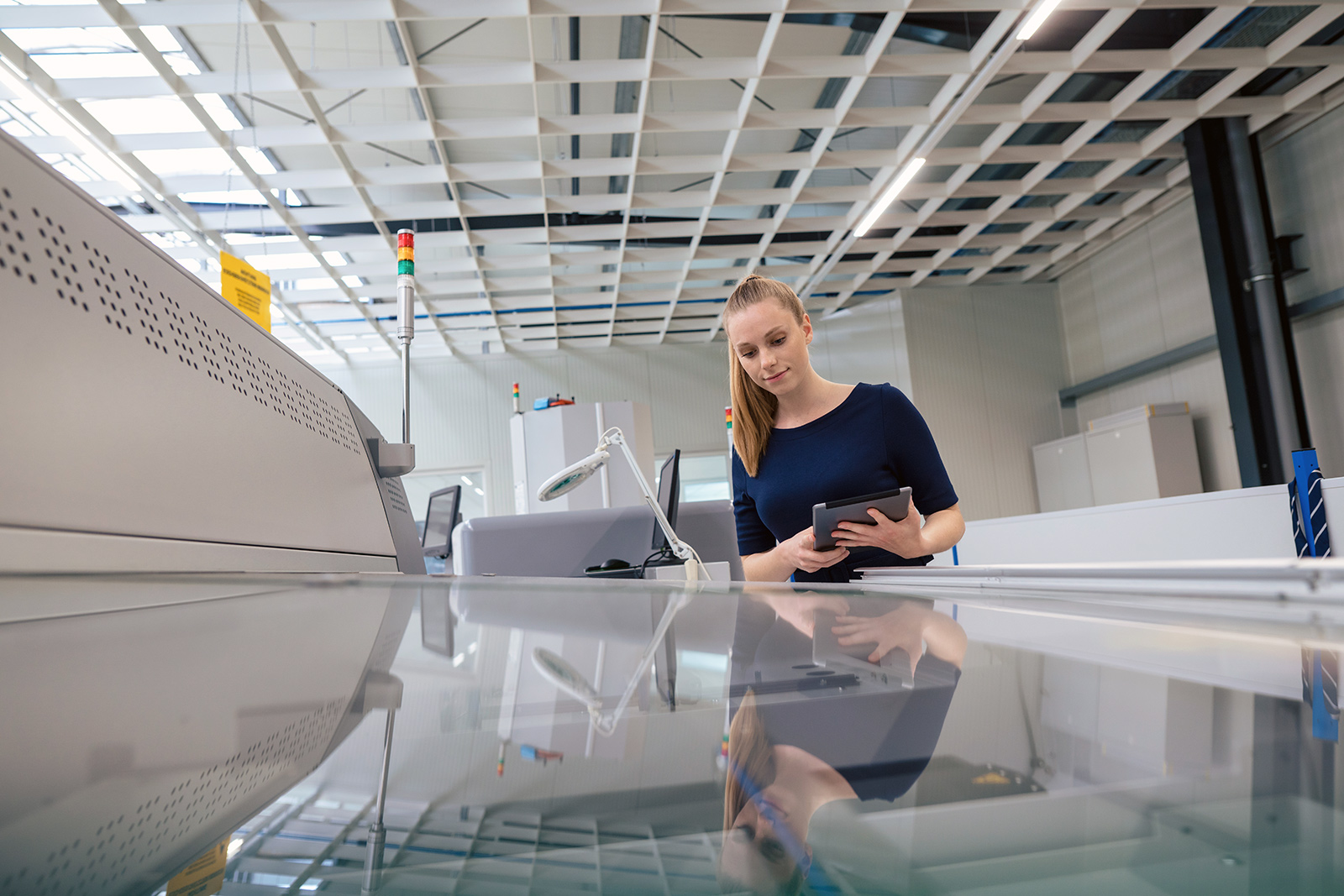 The image shows a woman in front of the printing press, operating it.