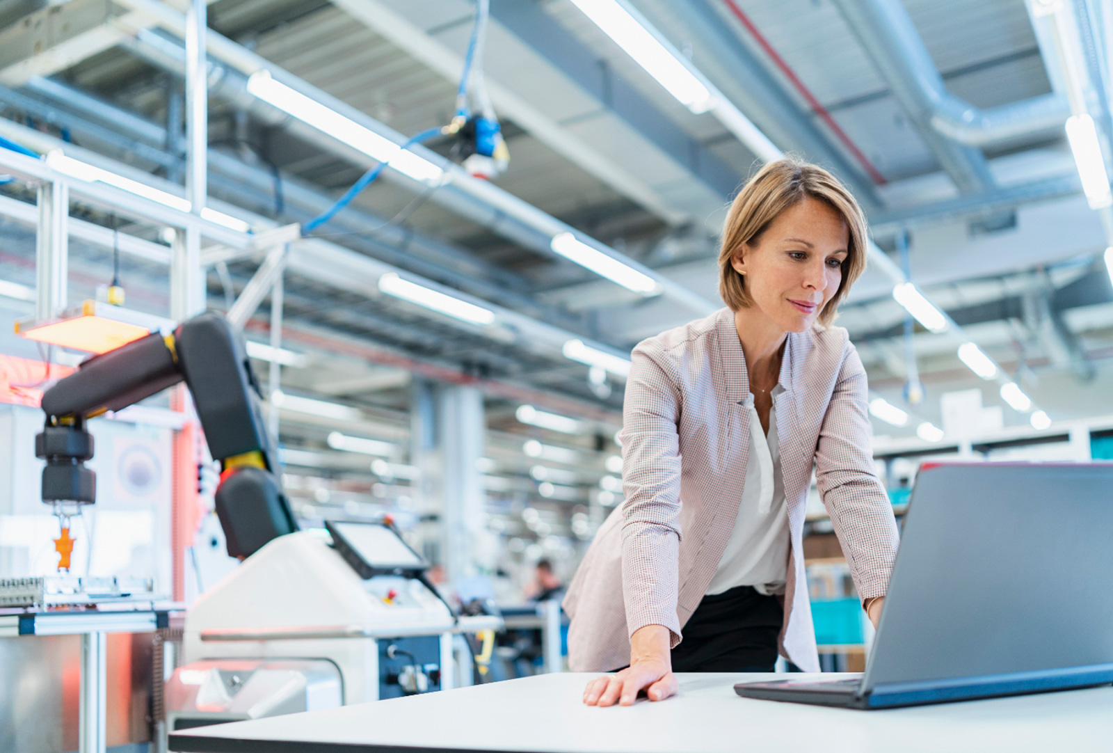 Woman standing at laptop in industrial hall