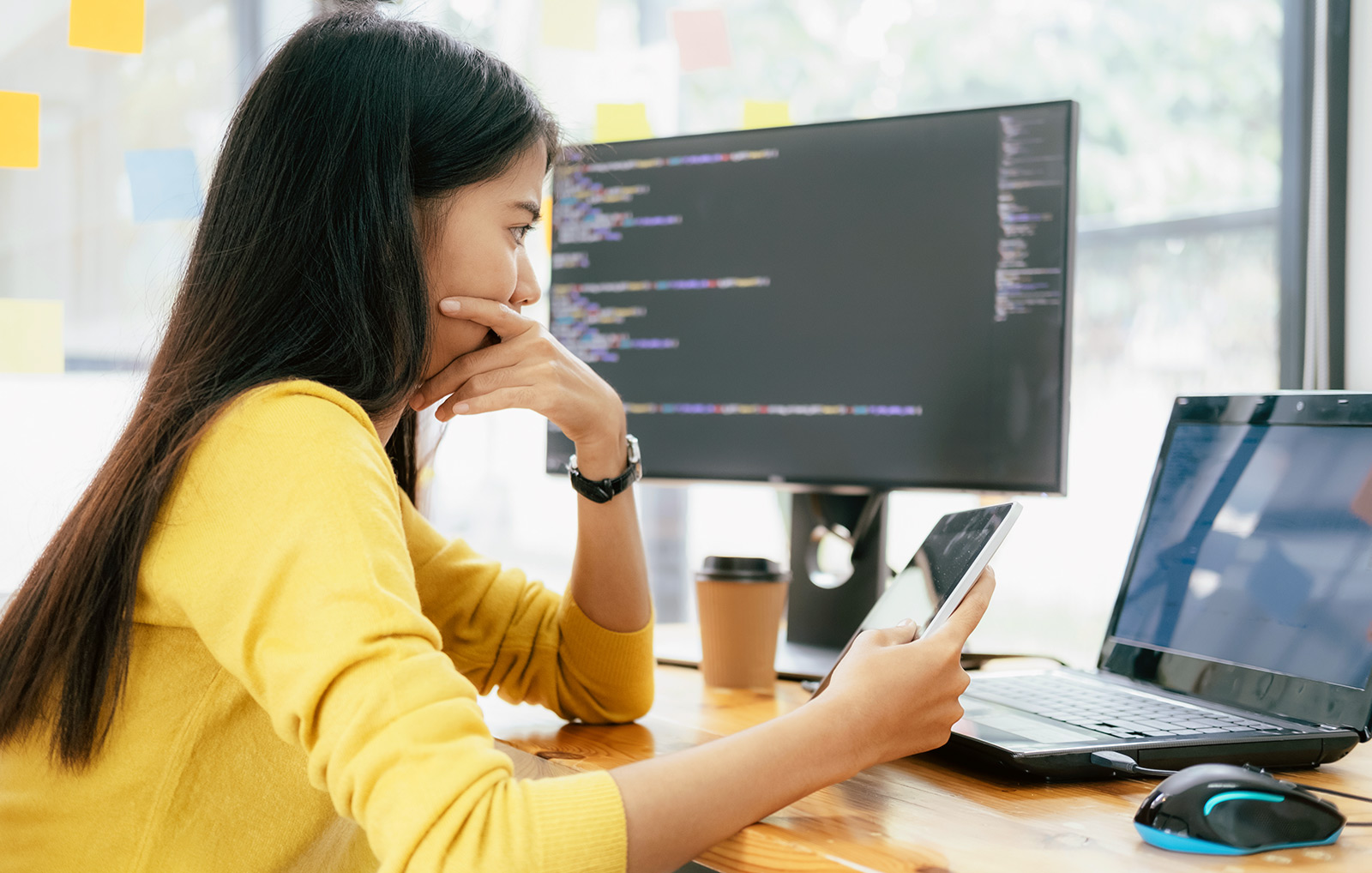 A woman works on her tablet and computer.