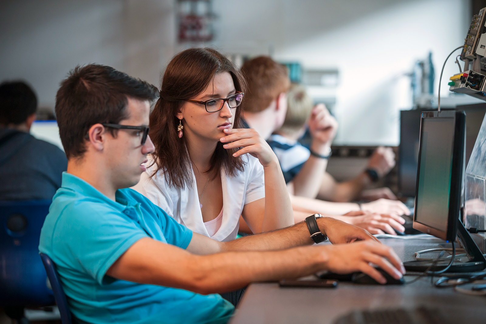 View of two people sitting in front of a computer.
