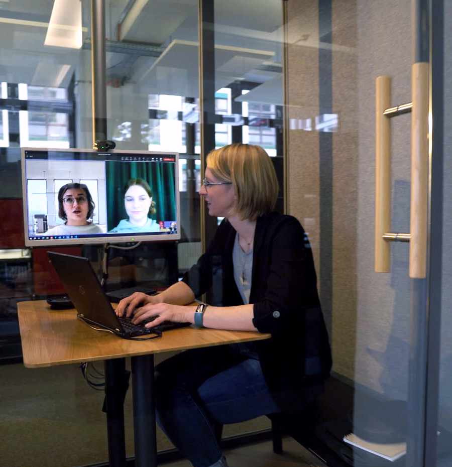 Foto von Rebecca Maier, IT-Administratorin bei der Bundesdruckerei, die in einer Besprechungskabine im Büro sitzt und an einer Videokonferenz teilnimmt