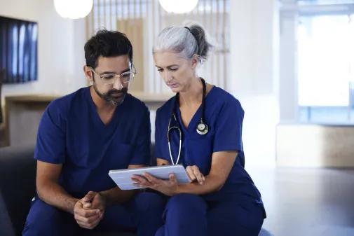 Ärztin und Arzt halten Tablet in der Hand