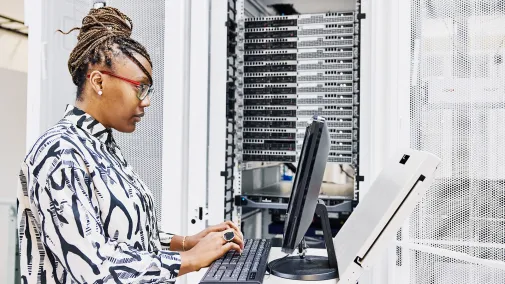 Eine Frau sitzt am Computer und arbeitet am Server.