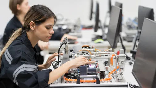 Frau sitzt am Schreibtisch und arbeitet mit einer Elektronikplatte.