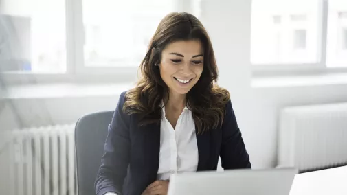 A woman works remotely on her laptop