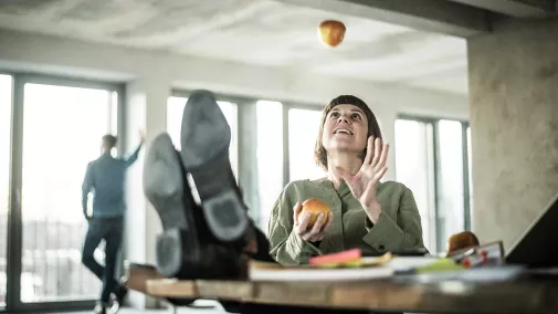 Frau sitzt im Büro uns isst einen Apfel 