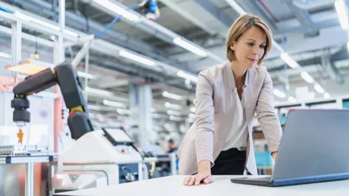 Frau steht am Notebook in Industriehalle Frau steht am Notebook in Industriehalle
