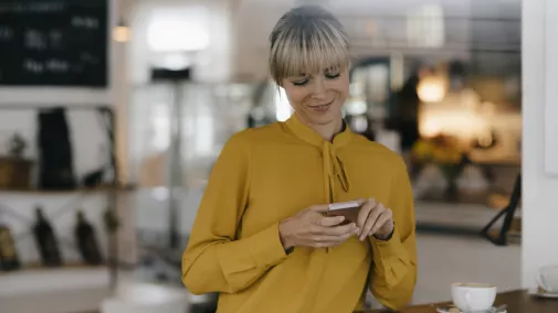 Frau liest auf Smartphone am Tisch im Büro