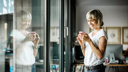women looks on her smartphone standing in office women looks on her smartphone standing in office