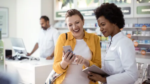 Zwei Frauen stehen mit Smartphone in Apotheke Zwei Frauen stehen mit Smartphone in Apotheke