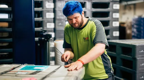 An employee is standing in the warehouse and opening a pallet.