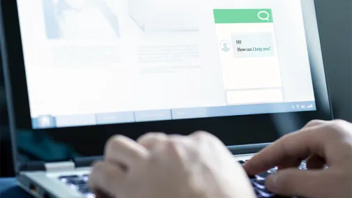 A close-up of a laptop screen showing a chatbot. You can see a pair of male hands typing and interacting with the chatbot.