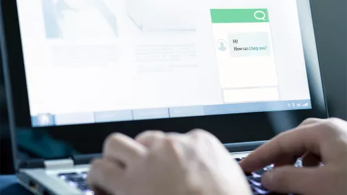 Künstliche Intelligenz Detailaufnahme eines Laptop-Bildschirms, auf dem ein Chatbot abgebildet es. Man sieht, wie männliche Hände etwas tippen und mit dem Chatbot interagieren.