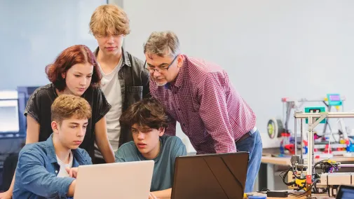 Teachers and students look at a computer