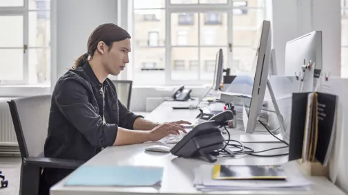 Mann sitzt am Computer am Schreibtisch im Büro Mann sitzt am Computer am Schreibtisch im Büro