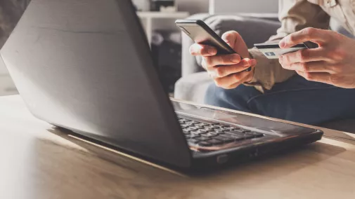 Detail Mannsitzt mit Notebook, Smartphone und Kreditkarte am Tisch Detail Mannsitzt mit Notebook, Smartphone und Kreditkarte am Tisch