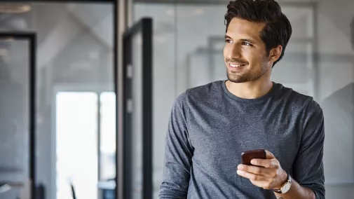 Mann mit Smartphone in der Hand im Büro