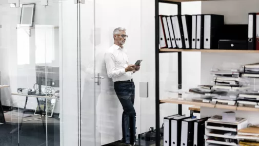 Mann steht mit Tabet im Büro Mann steht mit Tabet im Büro