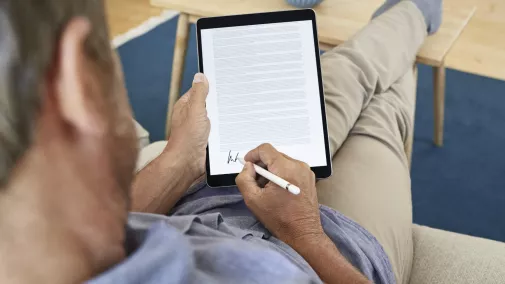 Mann mit Tablet unteschreibt digital von zu Hause