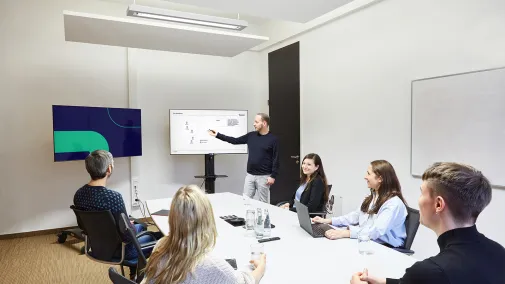 Foto mit Mitarbeitenden der Maurer Electronics GmbH, die an einem Konferenztisch sitzen und an einer Weiterbildung teilnehmen