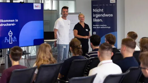 Zwei Mitarbeiter begrüßen die neuen Auszubildenden. 