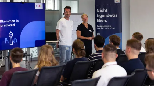 Zwei Mitarbeiter begrüßen die neuen Auszubildenden. 