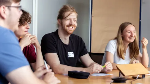 Ansicht von Auszubildenden die in einem Meeting zusammen sitzen.