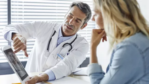 Doctor shows a patient X-ray images on a tablet Doctor shows a patient X-ray images on a tablet