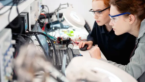 Zwei Frauen am Schreibtisch mit arbeiten an Elektronik.