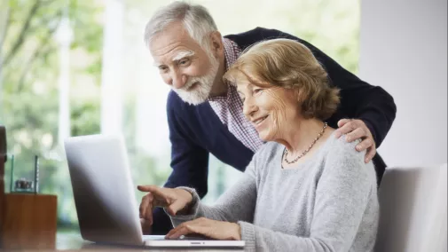 Rentner Frau und Mann sitzen mit Notebook am Tisch zu Hause