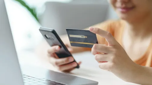 Eine Person hält eine Kreditkarte und Smartphone.