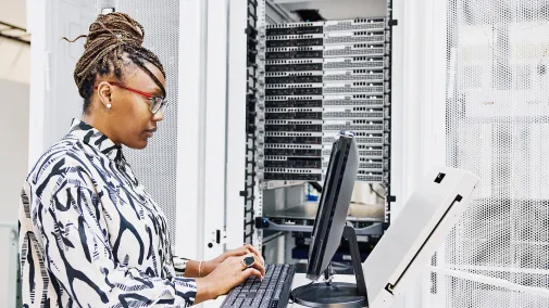 A woman sits at the computer and works on the server.