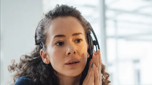 Woman wearing headphones looks intently at her laptop.