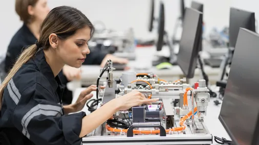 Woman sitting at a desk working with an electronic board.