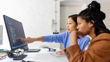 Zwei Frauen sitzen vor einem Bildschirm