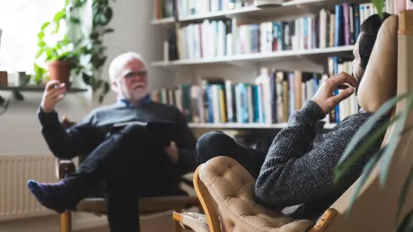 zwei Personen sitzen sich gegenüber in einer Therapiesitzung