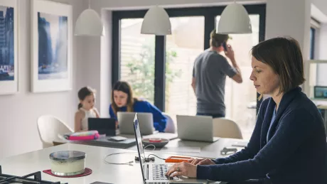 Frau mit Kindern und Mann zu Hause am Notebook