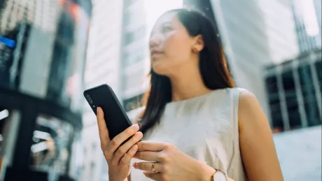 Frau mit Smartphone steht draussen vor Büro