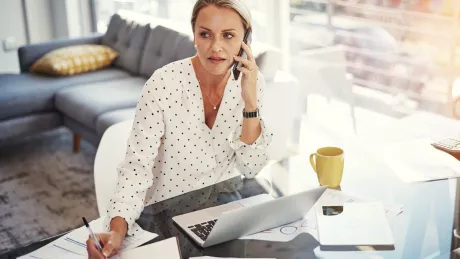 Frau mit Smartphone und Tablet am Tisch 