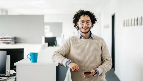 Mann mit Smartphone steht im Büro 