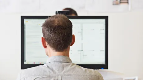 Mann sitzt am Computer und arbeitet