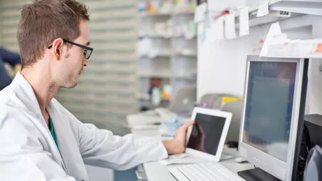 Mann Arzt am Computer mit Tablet im Labor