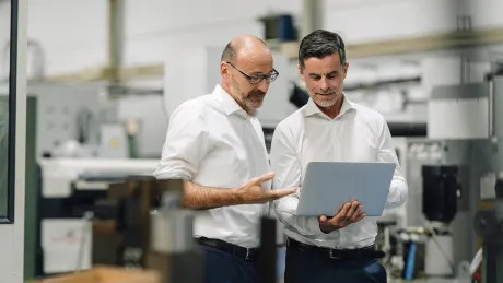 Geschäftsmänner mit Laptop in Produktionshalle